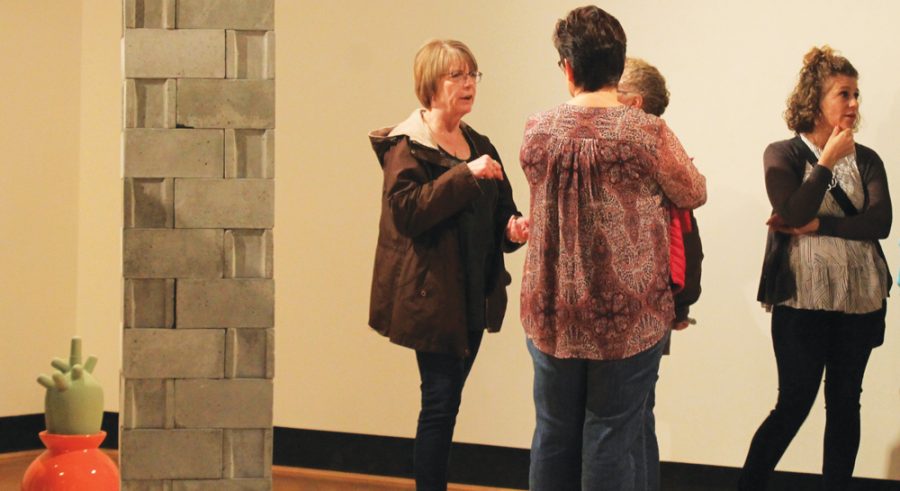 Community+member%E2%80%99s+discuss+Luke+Severson%E2%80%99s+gallery+near+the+cinder+block+wall+piece.