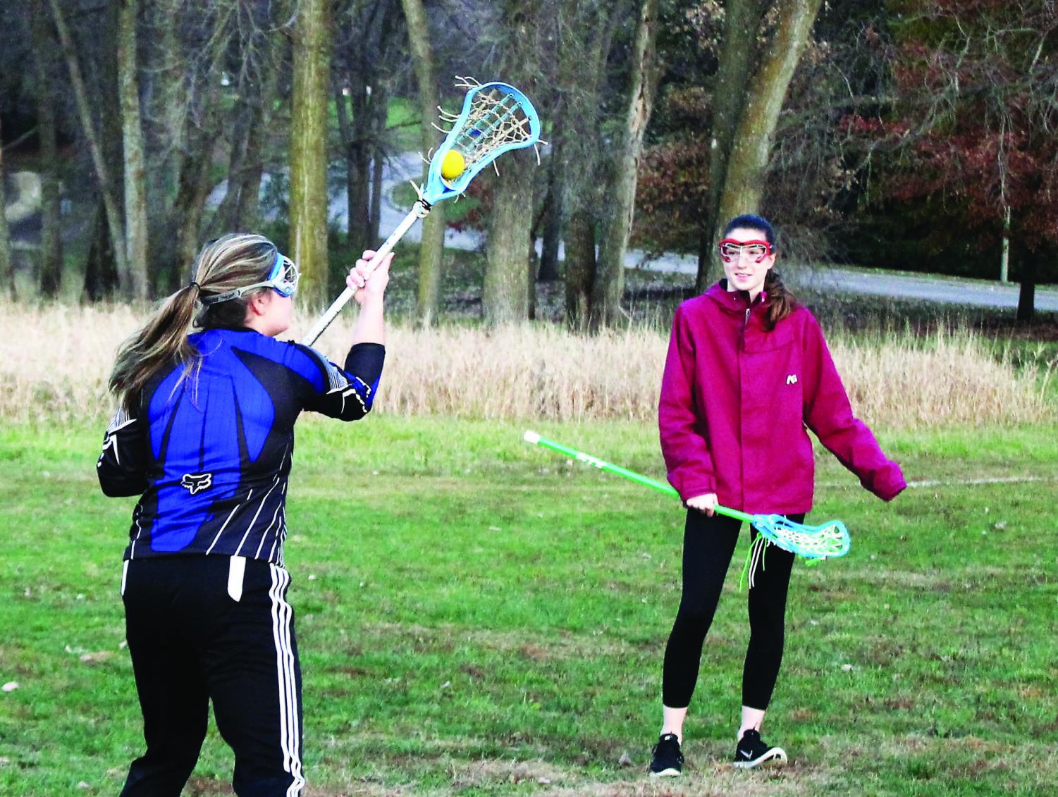 Fallon Cassidy (‘19) and Frances Rhodes (‘20) practice lacrosse skills by Lindeman Pond.