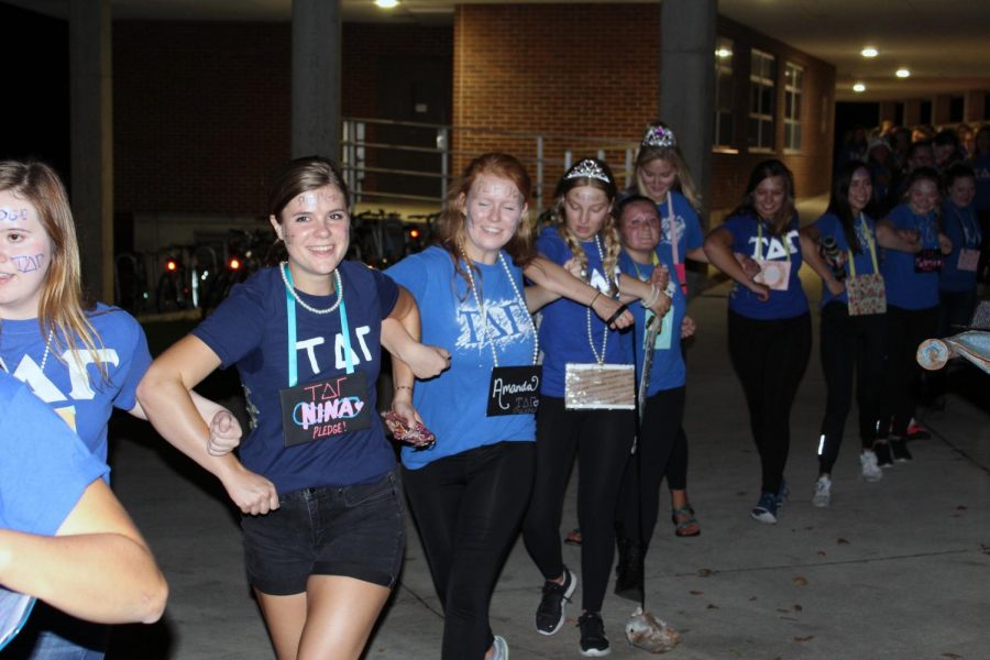 Nina+Johnson+%28%E2%80%9819%29+and+Amanda+Nyquist+%28%E2%80%9819%29+hook+elbows+and+walk+around+campus+with+other+pledges+on+pick+up+night+in+2017.