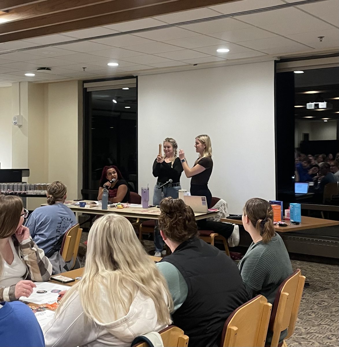 Sophia England (24, center) holds a wooden penis during a demonstration of putting on a condom at NASAs Condom Bingo event on November 6.