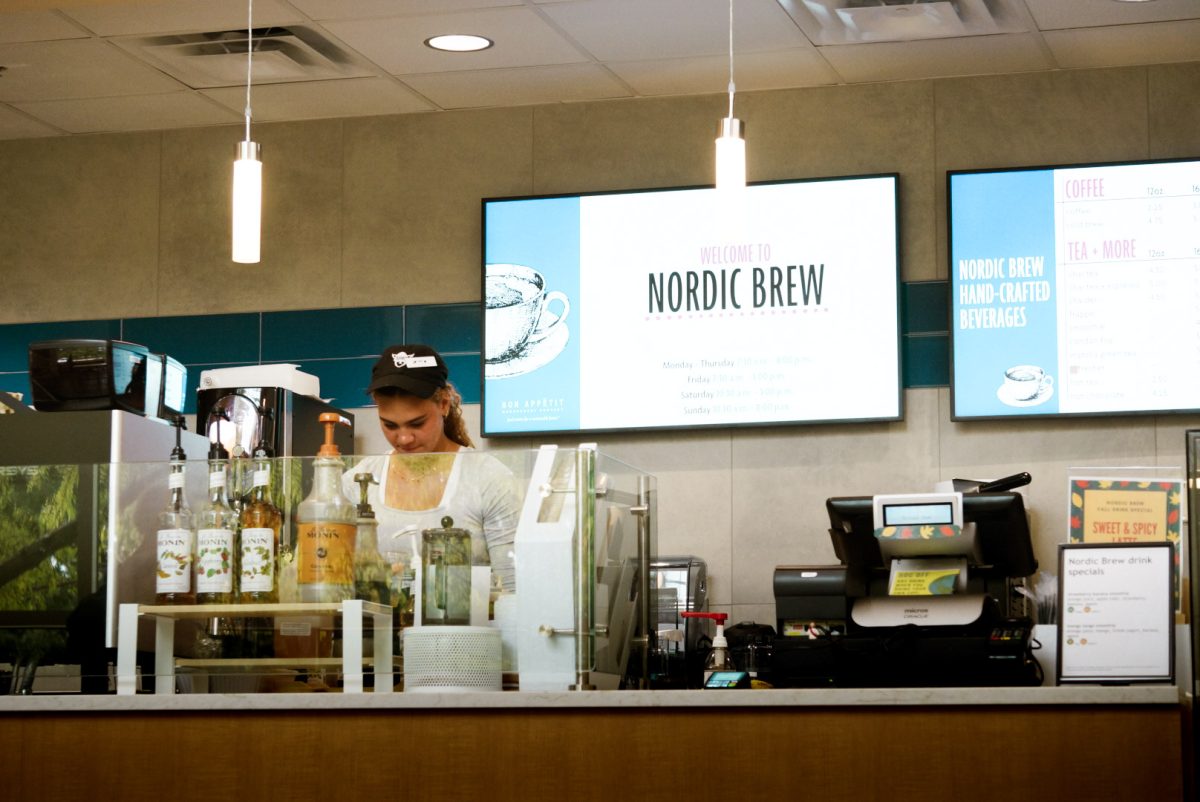 A young, female student barista working behind the counter at Nordic Brew, A coffee shop.